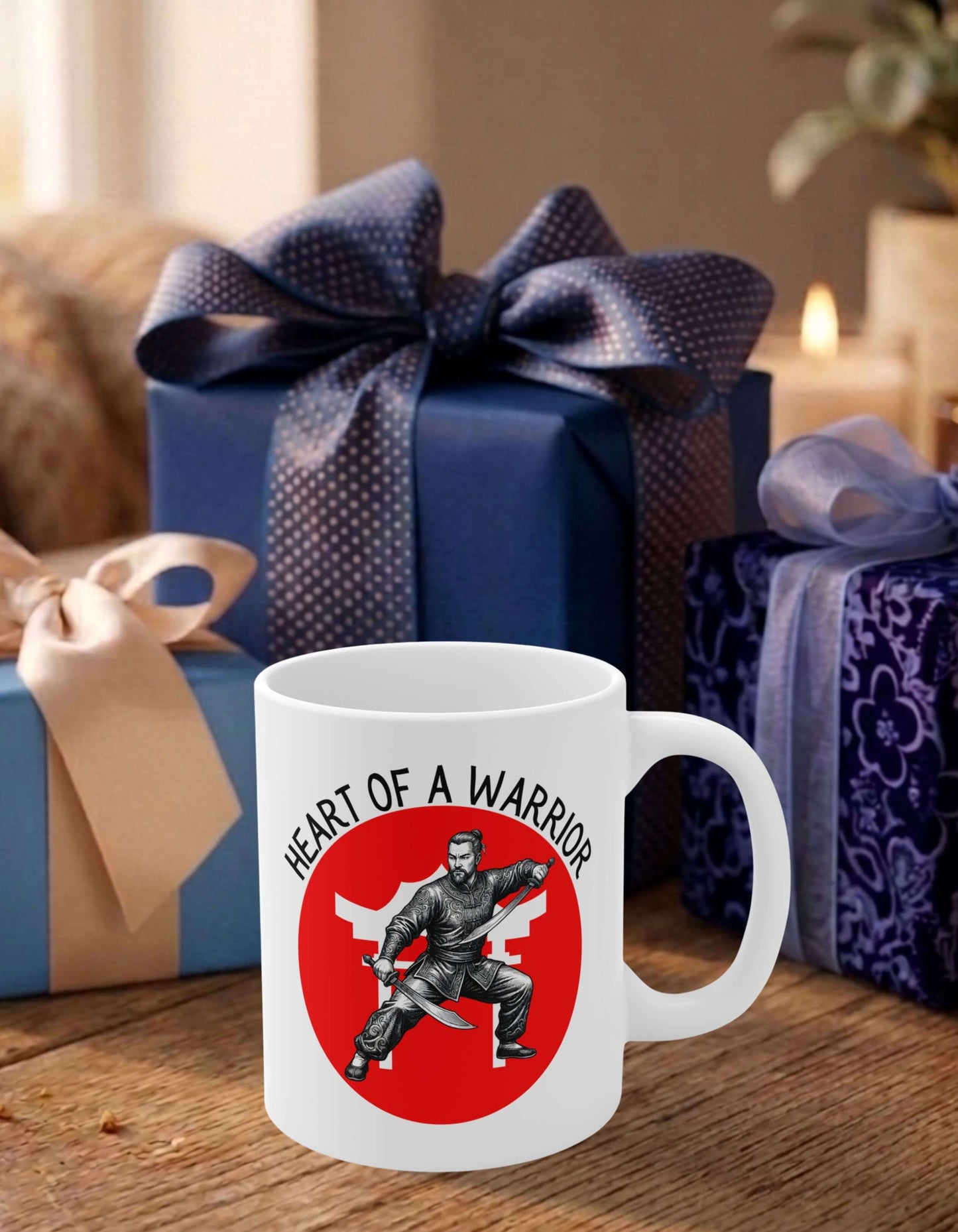 A white 11 oz ceramic mug featuring the slogan — Heart of a Warrior printed in black letters, above the graphic of a male warrior in fight stance wielding twin swords in front of the silhouette of a red Chinese Temple, sits on a wooden table, surrounded by thoughtfully wrapped gifts.