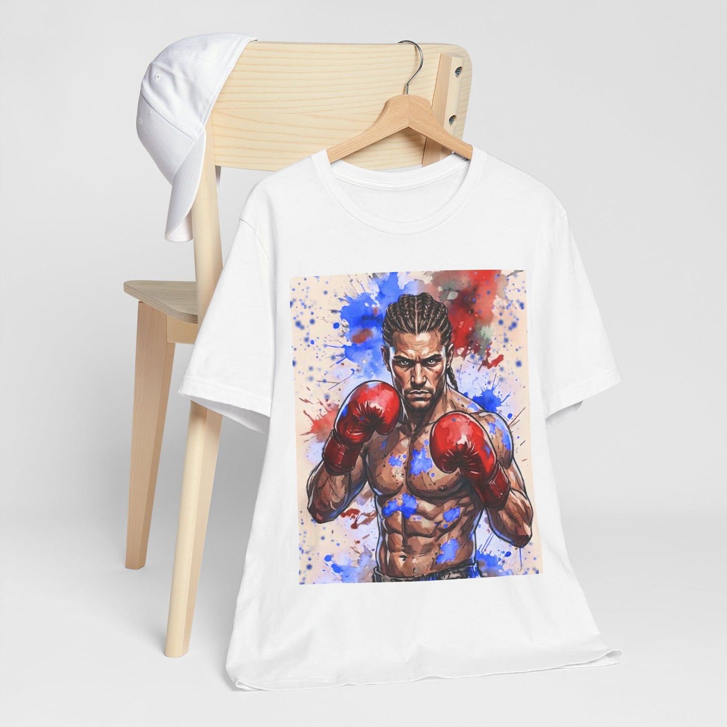 A white short-sleeve t-shirt on a wooden hanger, featuring a large graphic print of a muscular boxer wearing red boxing gloves. The shirt is styled in front of a light wood chair set against a clean light grey background.