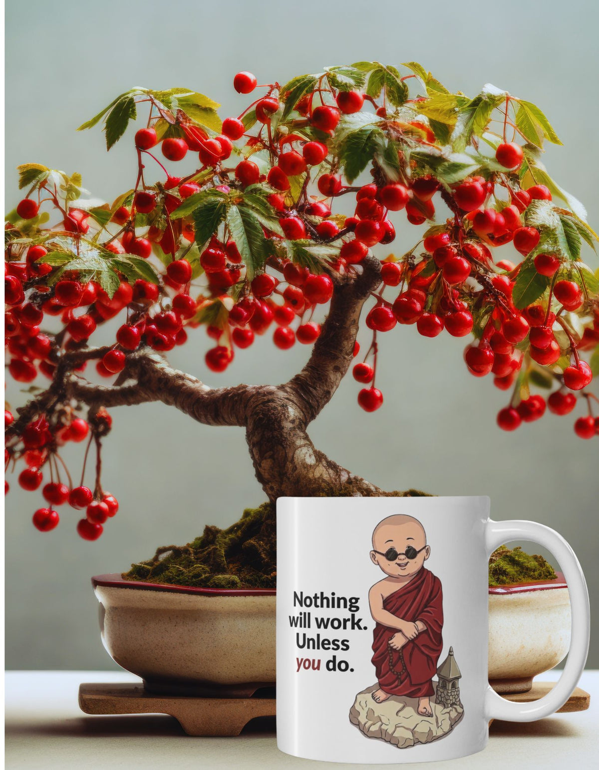 A white ceramic mug with an illustration of a monk wearing a red robe next to the text 'Nothing will work unless you do.' with a red berry bonsai tree in the background.