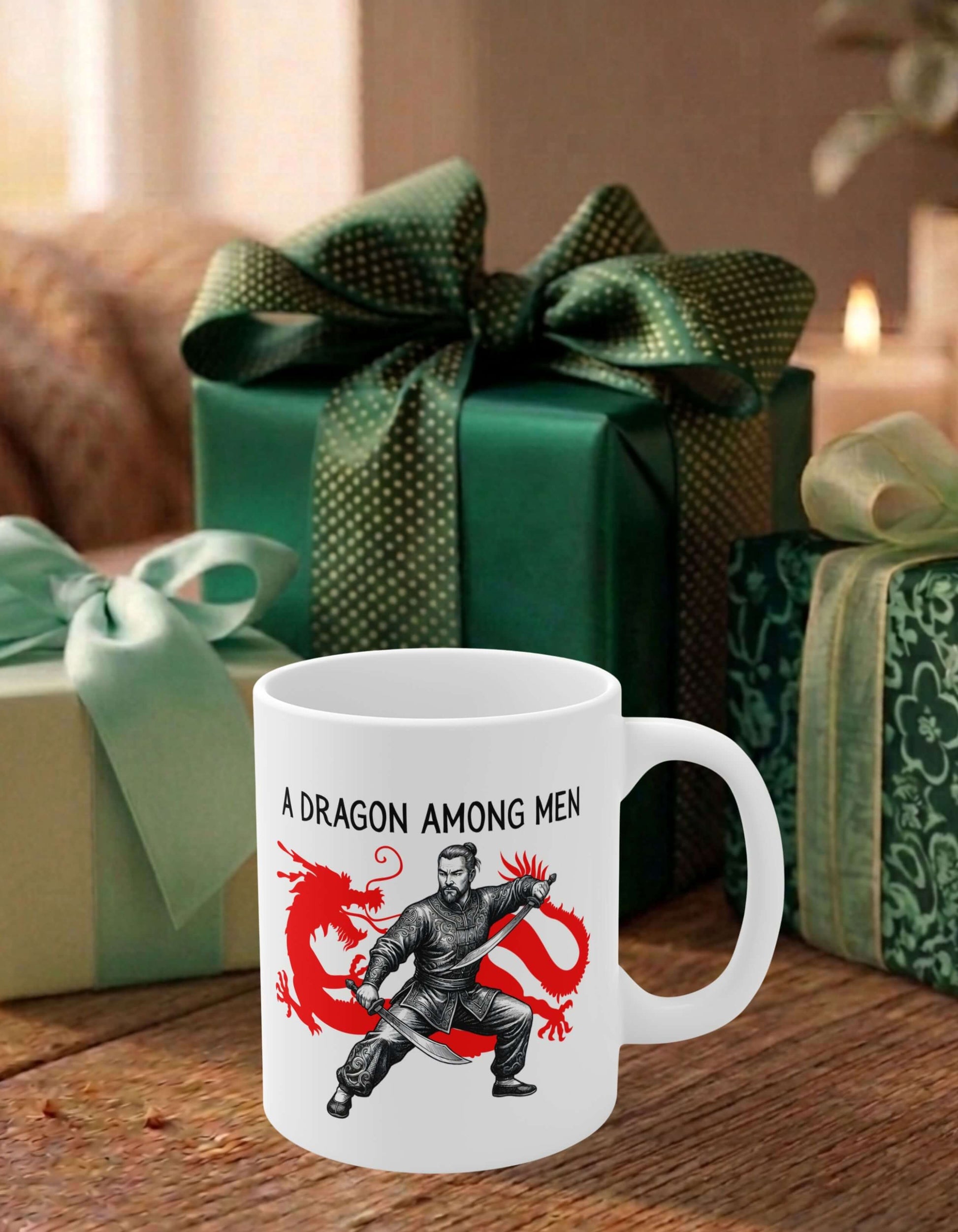 A white 11 oz ceramic mug featuring the slogan — A Dragon among Men printed in black letters, above the graphic of a steadfast male warrior in fight stance wielding twin swords in front of the silhouette of a red Chinese dragon; sits on a wooden table, surrounded by thoughtfully wrapped gifts.