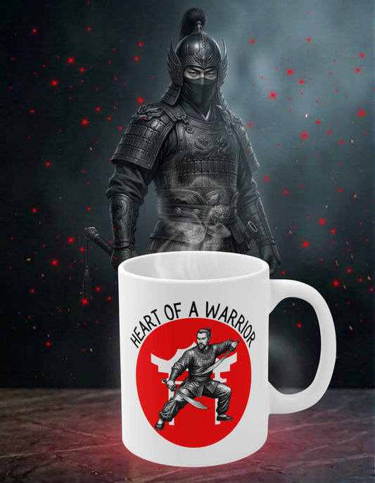 White 11 oz ceramic mug with the slogan — Heart of a Warrior printed in black letters, above the graphic of a male warrior in fight stance wielding twin swords, set against a bold white Chinese temple silhouette in a red circle; sits on a stone slab with a fierce warrior in the background. 