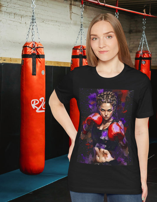 Woman wearing a Fighter Spirit black T-shirt featuring a powerful female boxer with red boxing gloves with a bold purple and red paint splatter background, standing in a boxing gym.
