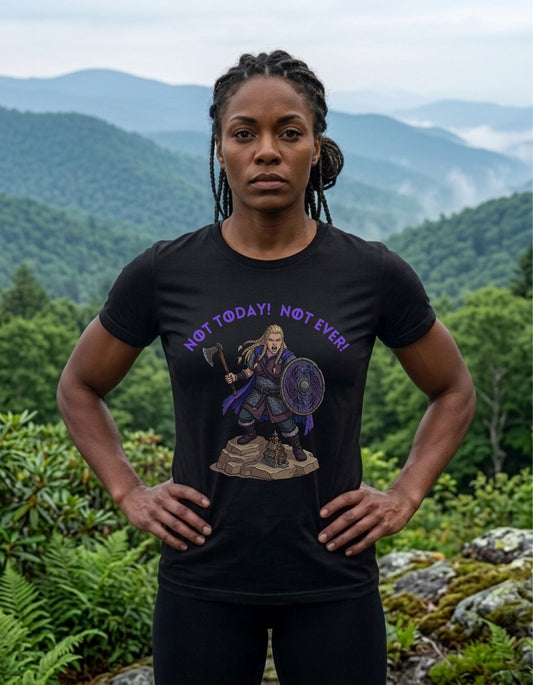 A woman standing outdoors in front of misty mountains and green forest, wearing a black graphic T-shirt with purple text reading 'NOT TODAY! NOT EVER!' above the design of a female Viking warrior holding an axe and shield.