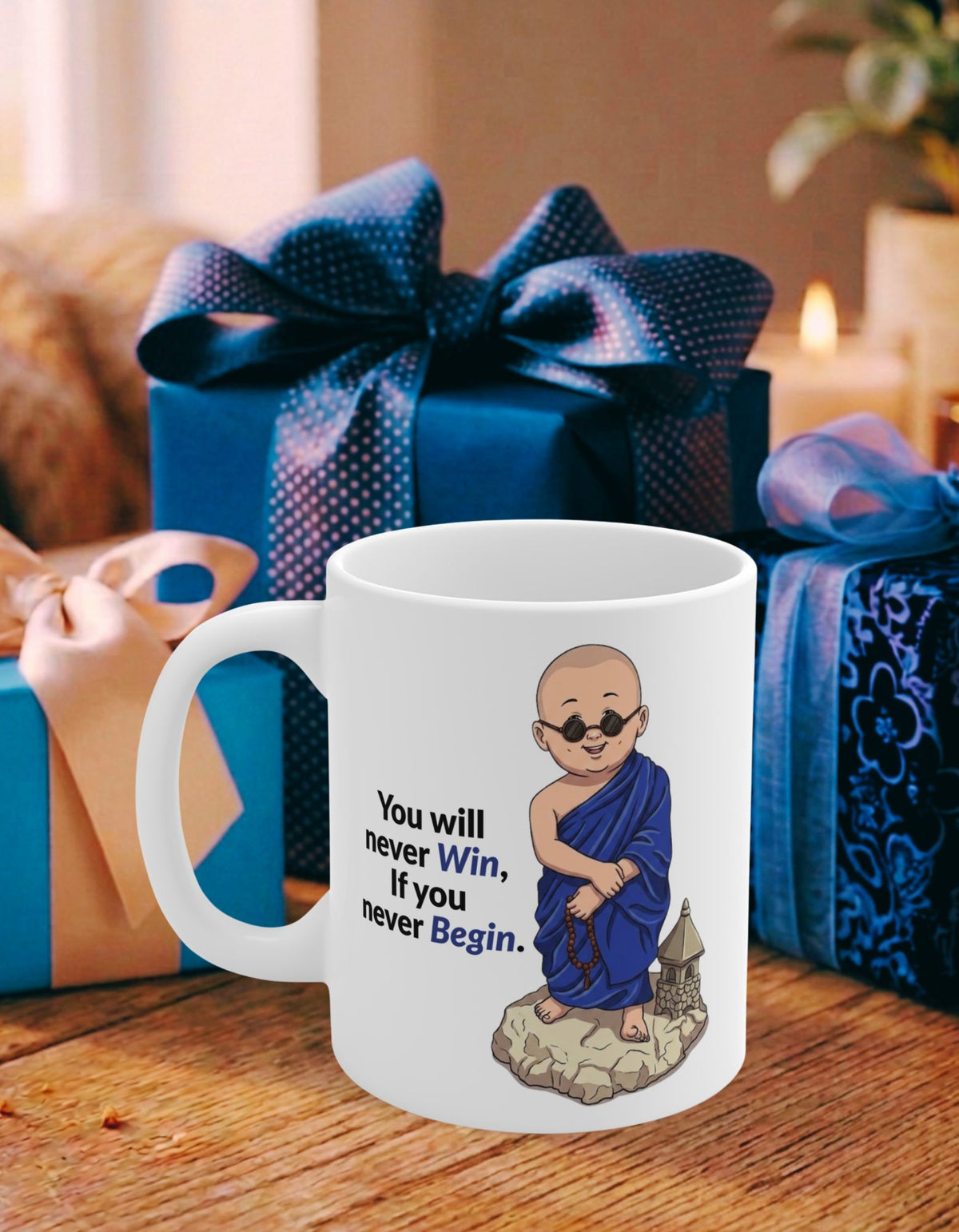A white ceramic mug with an illustration of a monk in blue robes and the text 'You will never Win, if you never Begin.' It is placed on a wooden table in front of blue wrapped gift boxes.